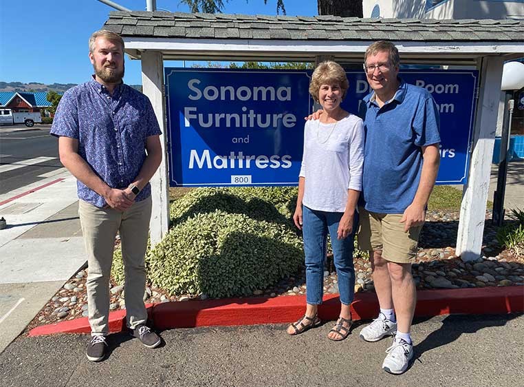 Business owners posing for a photo by the store sign