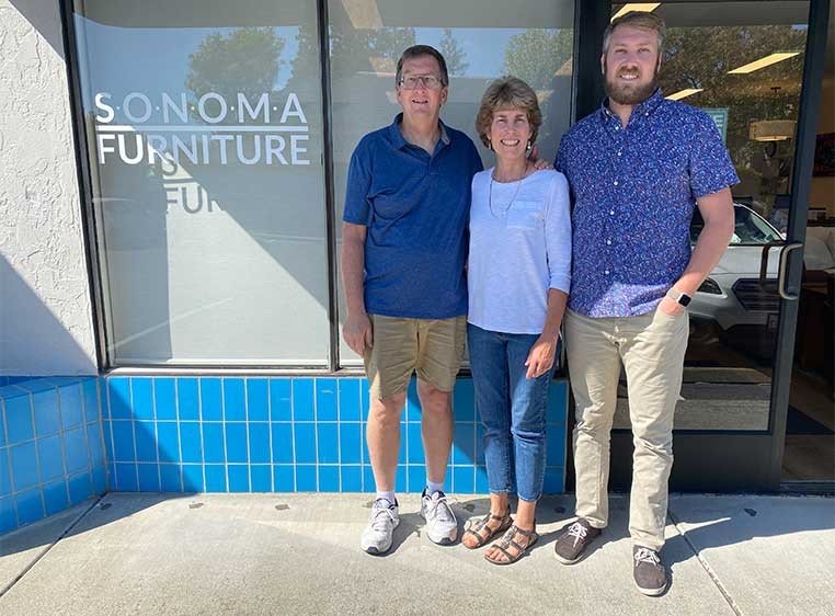 Business owners posing for a photo together by the storefront